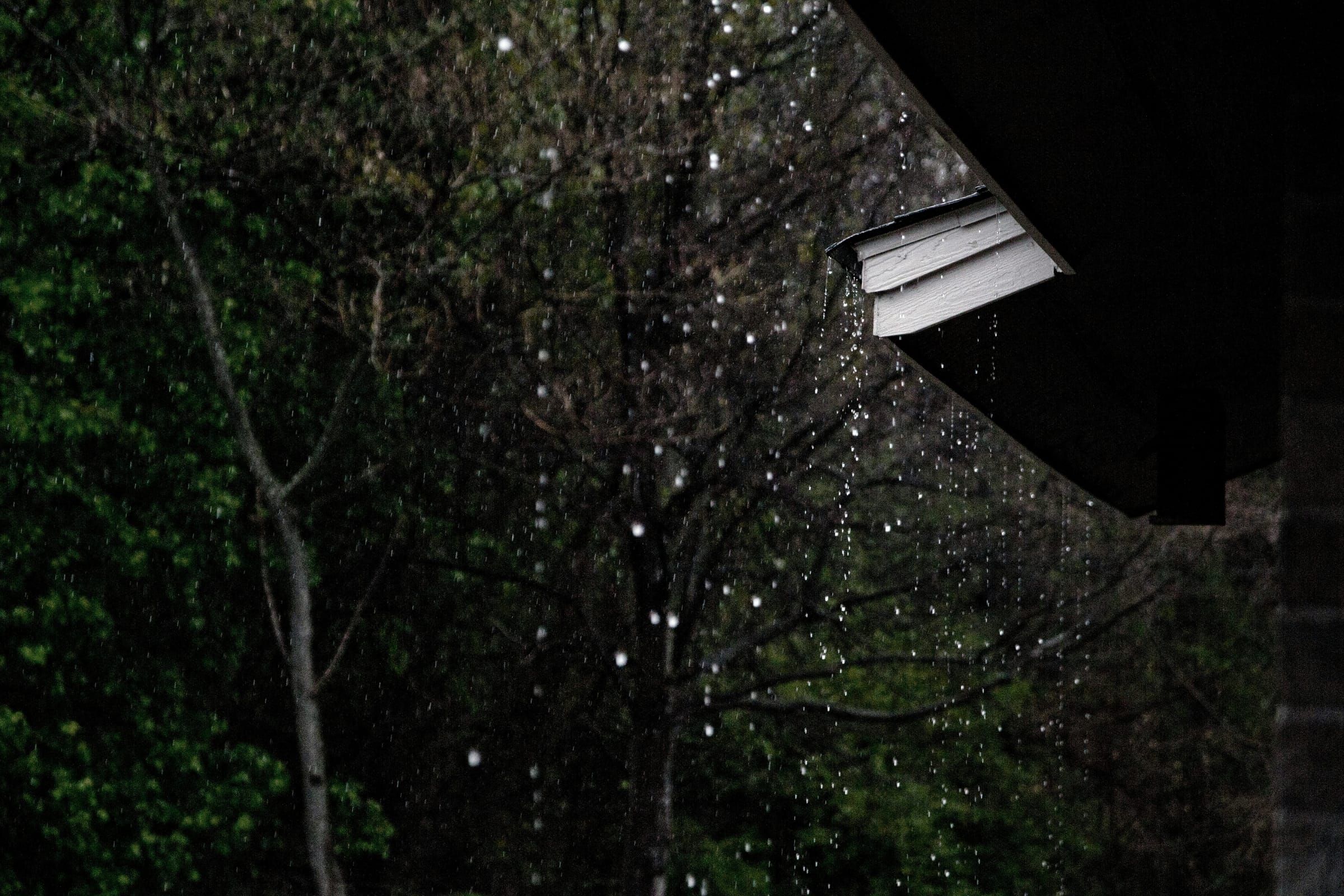Rainwater overflowing a gutter at night