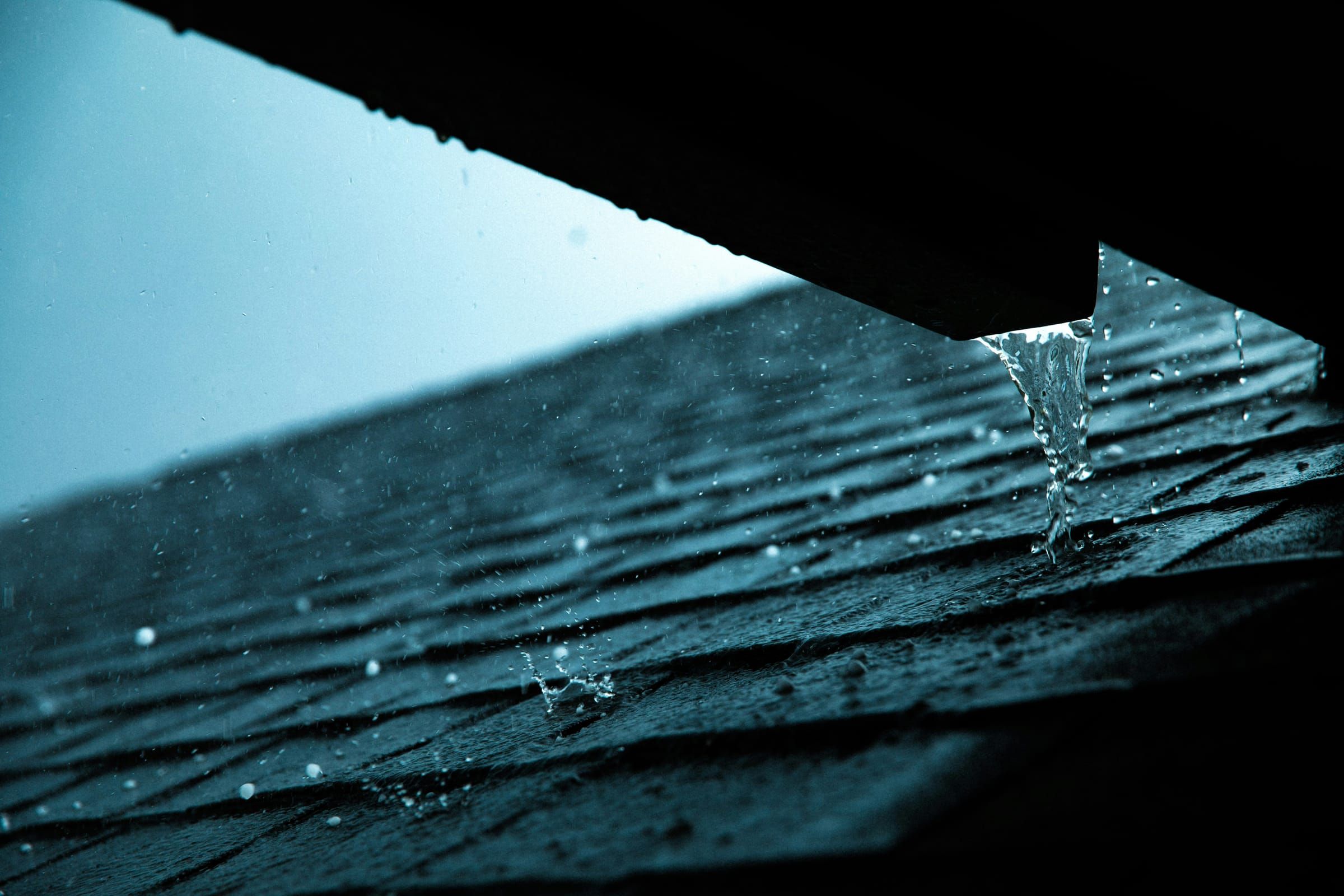 Rain running off the edge of a shingle roof